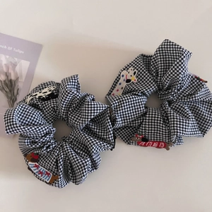Detail shot of black and white gingham hair scrunchies with cute animal embroidery