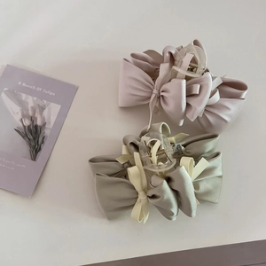 Elegant satin bow claw clips in pink and green displayed on a minimalist background