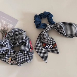 Detail of plaid scrunchie and bow hair tie featuring dachshund and puppy embroidery