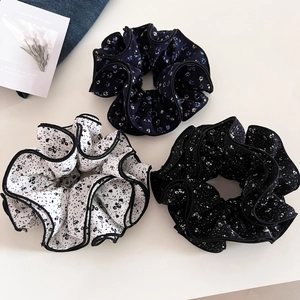 Detailed flat lay of three floral scrunchies in white, navy, and black with ruffled edges