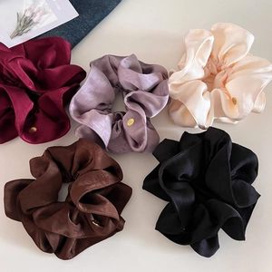 Vue à plat de cinq chouchous en satin assortis avec étiquettes dorées et texture lisse
