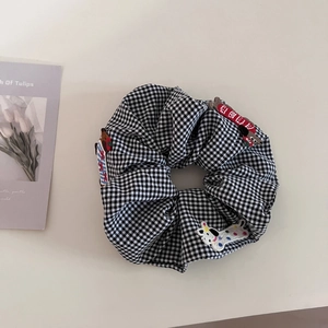 Close-up of black and white plaid scrunchie with cute animal patches and embroidery details