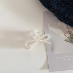 Detailed macro view of an elegant white acetate bow hair claw with iridescent pearly finish