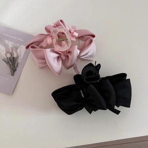 Detail view of large satin bow hair claws in pink and black with spring closure mechanism