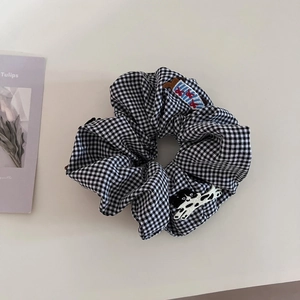 Detailed view of checkered scrunchie with cute cartoon dog patch and woven label