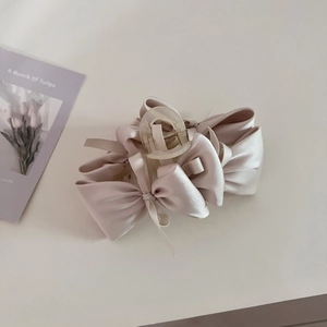 Detailed view of the large champagne pink satin bow hair claw clip with silk texture