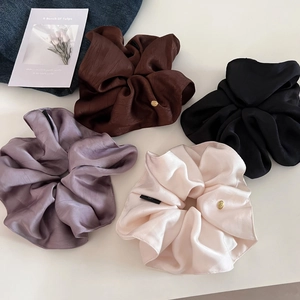 Elegant satin silk scrunchies in brown, black, purple, and cream with gold accents