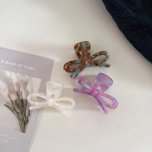 Three elegant acetate bow hair claws in tortoiseshell, white, and purple watercolor styles