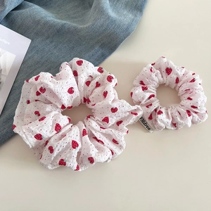 Detailed flat lay of sweet strawberry scrunchies with pleated texture and polka dots