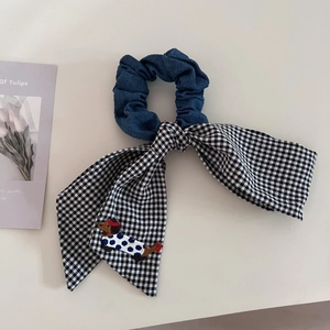 Detail of dachshund embroidery on blue denim and checkered bow scrunchie hair tie
