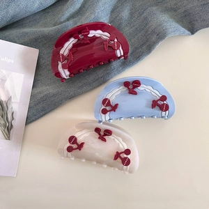 Detailed view of acetate hair claws in red, blue, and cream with cute cherry accents
