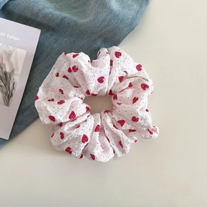 Detail of white strawberry print scrunchie with seersucker texture on denim background