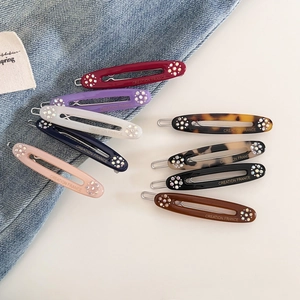Oval acetate hair clips in assorted colors with diamond rhinestones and gold logo