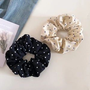 Lot de chouchous à pois en noir et beige présentés sur un fond minimaliste et épuré