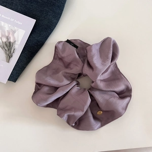 Elegant mauve satin scrunchie with a gold logo charm on a vintage tulip card background