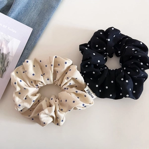 Détail du tissu à pois et étiquette de marque sur chouchous beige et noir