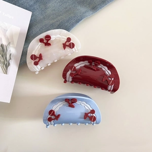 Close-up of semi-circular cherry claw clips in pearl white, wine red and light blue