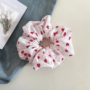 Close-up of a sweet strawberry print scrunchie on a cozy desktop background