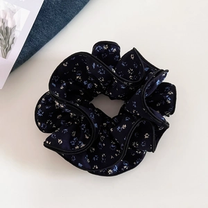 Detailed close-up of dark blue floral scrunchie with delicate four-layer pleated edges