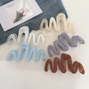 Five assorted wavy claw clips in glossy acrylic, showcased on a minimalist white backdrop