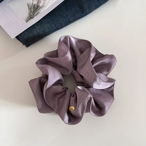Chouchou en satin lilas avec texture soyeuse et étiquette dorée sur fond blanc