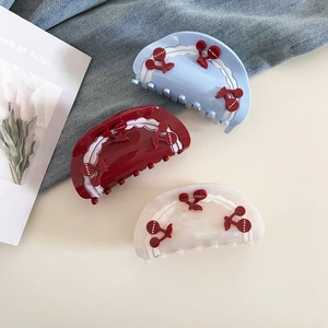 Close-up of sweet cherry acetate hair claws in blue, red, and white on a flat lay table