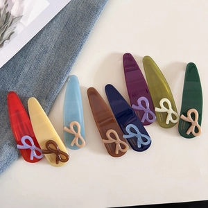 Set de 8 barrettes à nœuds en acétate coloré avec lettrage doré sur fond blanc pur