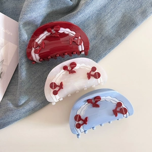 Close-up of three half-round hair claws in red, white, and blue with cherry patterns