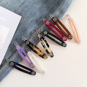 Macro detail of nine colorful oval hair clips with sparkling rhinestones and metal springs