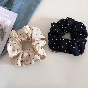 Gros plan de chouchous à pois beige et noir avec étiquette FMdrea et carte de tulipes