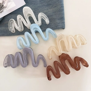 Detail showing five wave-shaped large hair claw clips in various marble gradient colors