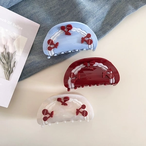Detailed view of cherry acetate hair claws in blue, red, and pearl white set of three
