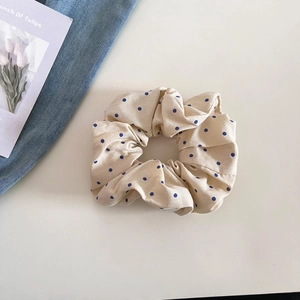 Gros plan d'un chouchou beige à pois bleus sur un fond blanc propre et épuré
