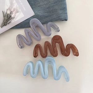Three wavy resin hair claws in grey-purple, amber brown, and light blue colors