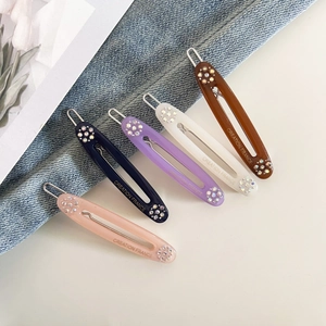 Macro detail of oval resin hair clips with rhinestones and Creation France lettering
