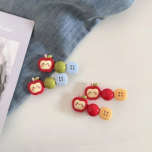 Gros plan de barrettes à cheveux pomme et bouton sur fond de denim et de magazine