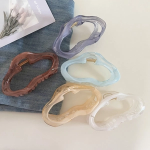 Detail of five large jelly-colored cloud hair claws on denim fabric and tulip card