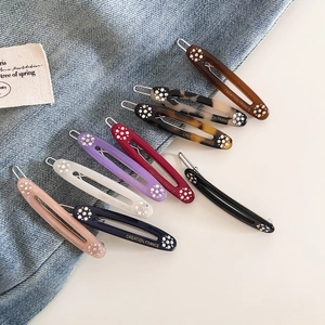 Macro view of nine assorted colorful acetate hair clips with crystal accents and engraving