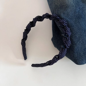 Detail of navy blue polka dot headband featuring built-in clips for styling hair