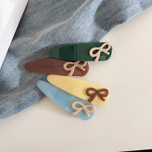 Détail des barrettes nœud en acétate en plusieurs couleurs avec inscription dorée élégante