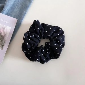 Gros plan détaillé d'un chouchou en tissu noir à pois blancs avec une texture en coton doux