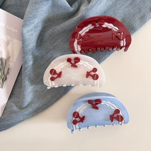 Close-up of sweet cherry claw clips in red, white, and blue on denim background