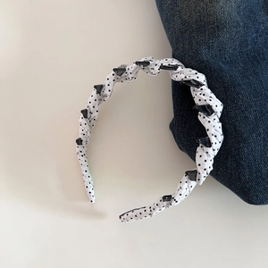 Polka dot fabric headband featuring small black clips for securing hair details