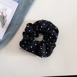 Détail du chouchou noir à pois avec étiquette de marque sur un fond de style de vie