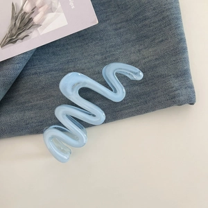 Detail of light blue wave hair claw clip on denim background with tulip card decoration