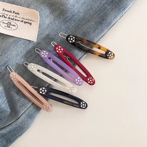 Detailed view of six French style acetate hair clips with rhinestones and gold lettering