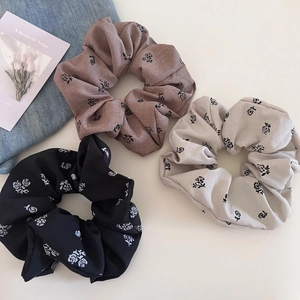 Close-up of three vintage cotton scrunchies with black rose patterns in black, brown, and grey