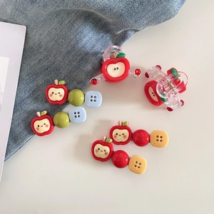 Détail de pinces à cheveux pomme rouge et boutons colorés sur fond en jean clair