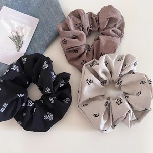 Detailed view of floral scrunchies in black, brown, and beige with rose patterns