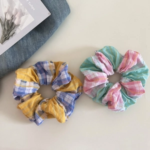 Close-up of two colorful plaid fabric scrunchies for hair ties in blue and pink patterns